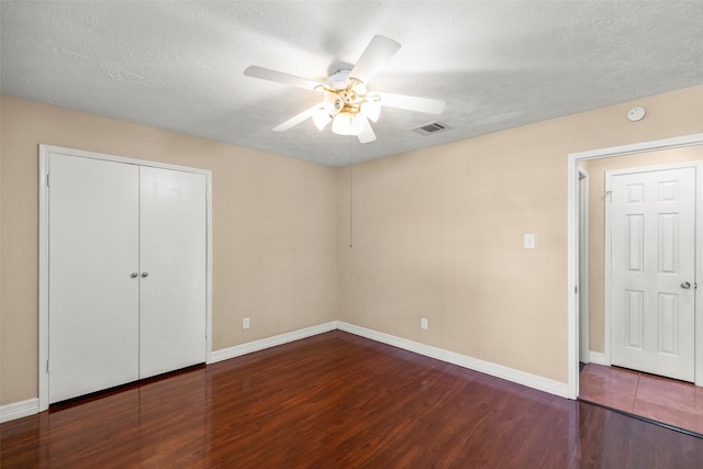 unfurnished bedroom with a closet, visible vents, a textured ceiling, and wood finished floors