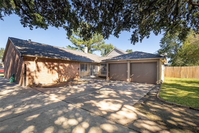 single story home with an attached garage, brick siding, fence, driveway, and a front lawn