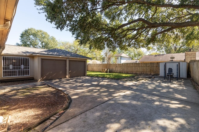 exterior space with an outbuilding, concrete driveway, a fenced backyard, and a storage unit