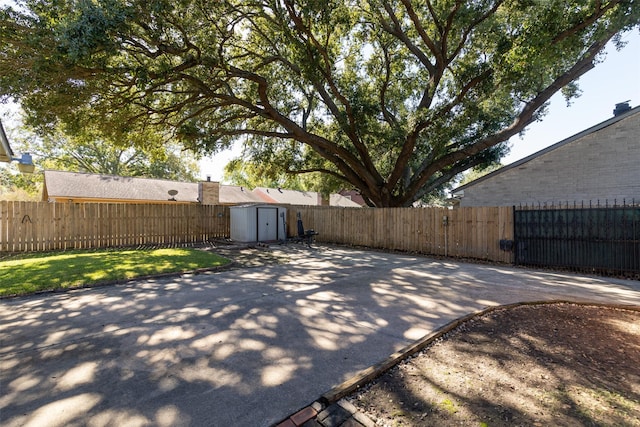 exterior space featuring a storage shed, a fenced backyard, a gate, and an outbuilding