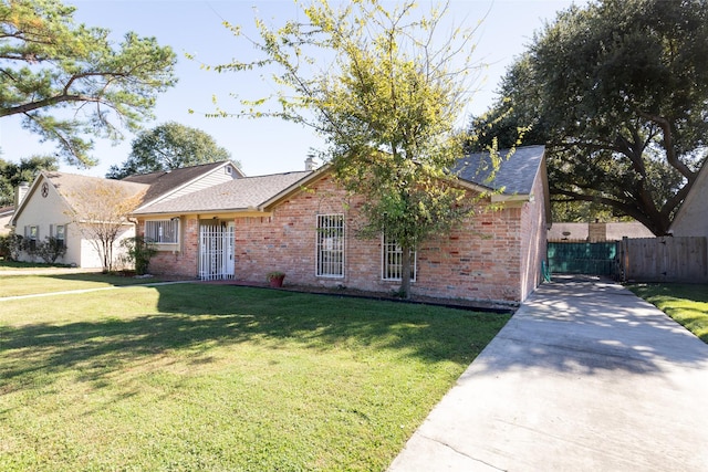 ranch-style home featuring driveway, fence, a front lawn, and brick siding