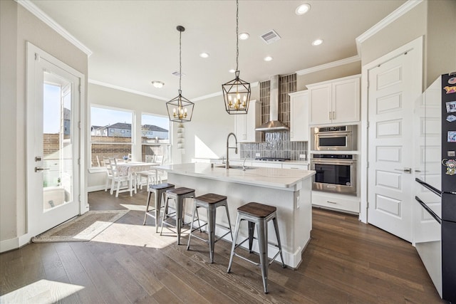 kitchen featuring a sink, visible vents, decorative backsplash, wall chimney exhaust hood, and dark wood finished floors