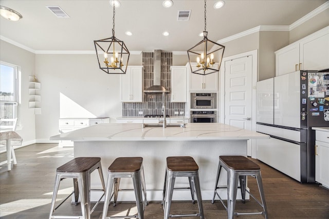 kitchen with visible vents, wall chimney exhaust hood, freestanding refrigerator, and decorative backsplash