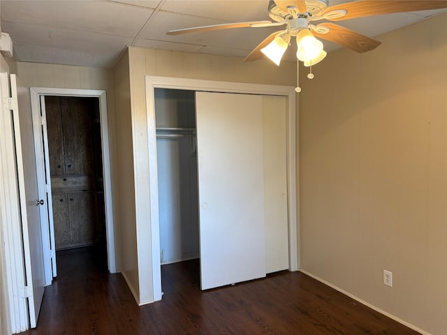 unfurnished bedroom featuring a closet, dark wood finished floors, and a ceiling fan