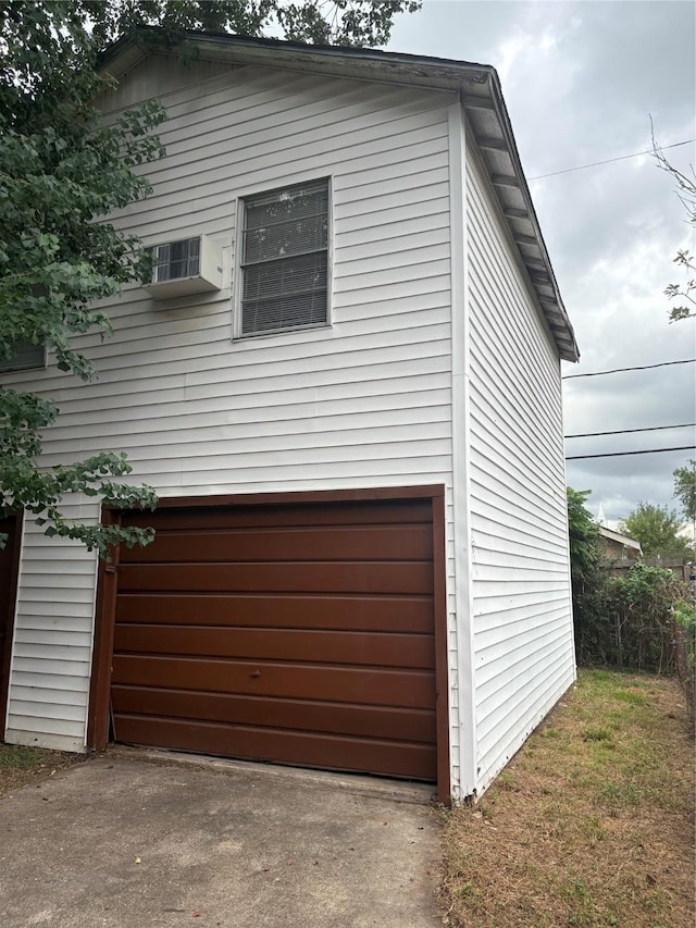 view of property exterior featuring a garage and a wall unit AC