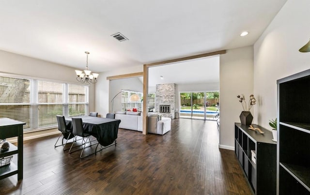 dining space featuring recessed lighting, a notable chandelier, dark wood-style flooring, a fireplace, and visible vents