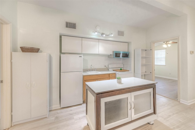 kitchen featuring stainless steel microwave, visible vents, freestanding refrigerator, a sink, and range