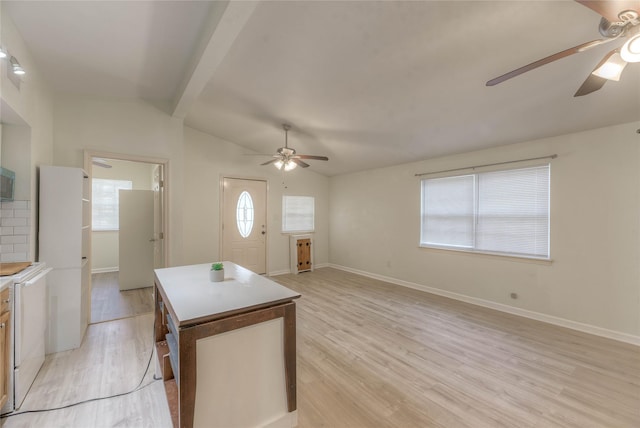 kitchen with vaulted ceiling with beams, light wood finished floors, a kitchen island, ceiling fan, and baseboards