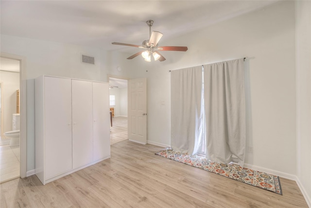 empty room with a ceiling fan, visible vents, light wood-style flooring, and baseboards