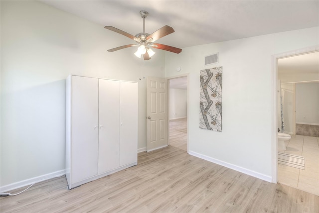 unfurnished bedroom featuring lofted ceiling, light wood finished floors, visible vents, and a closet