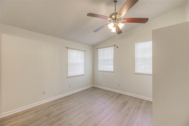 spare room featuring vaulted ceiling, ceiling fan, light wood-type flooring, and baseboards