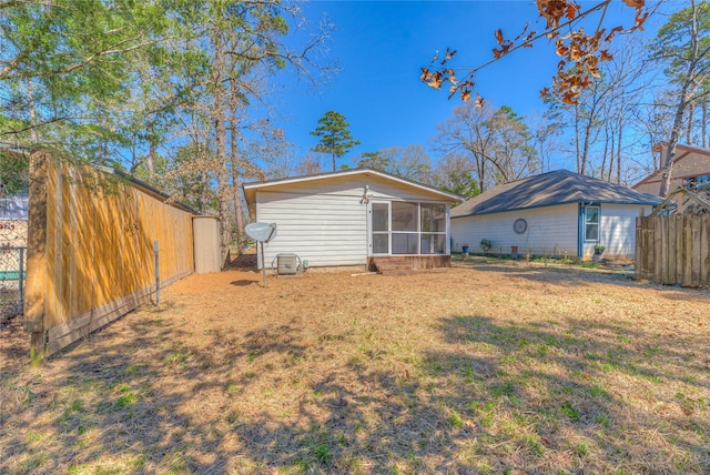 back of house with a sunroom, fence, and a lawn