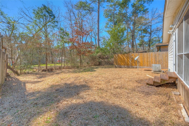 view of yard with central air condition unit and fence