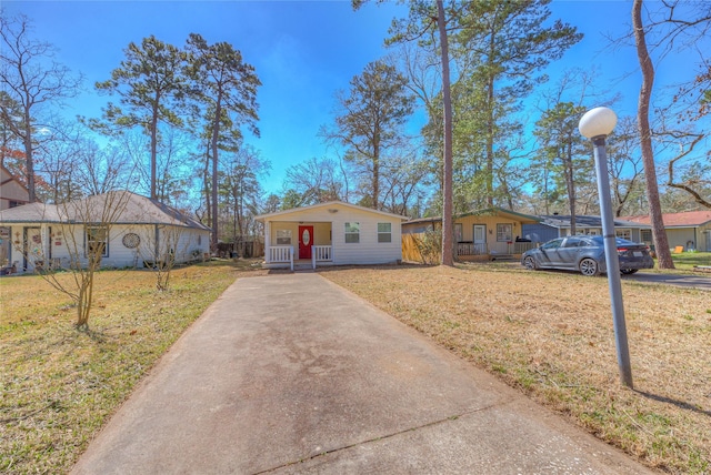 view of front of home with driveway, covered porch, and a front lawn