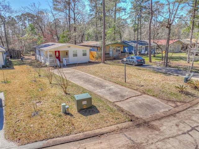 ranch-style home featuring a porch, a residential view, concrete driveway, and a front lawn