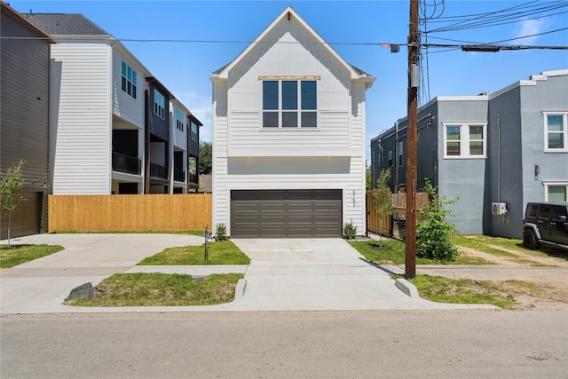 view of front of house featuring a garage, concrete driveway, fence, and board and batten siding