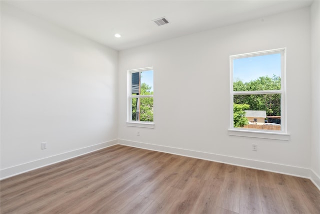 spare room featuring light wood-type flooring, baseboards, visible vents, and recessed lighting