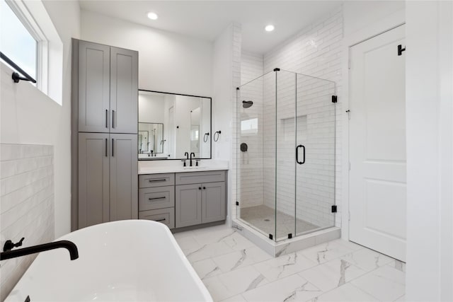 full bath with marble finish floor, vanity, a freestanding tub, a shower stall, and recessed lighting