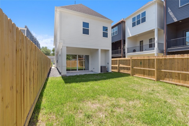 rear view of house featuring a fenced backyard, a yard, central AC, and a patio