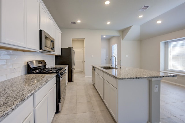 kitchen with visible vents, appliances with stainless steel finishes, a kitchen island with sink, a sink, and white cabinetry