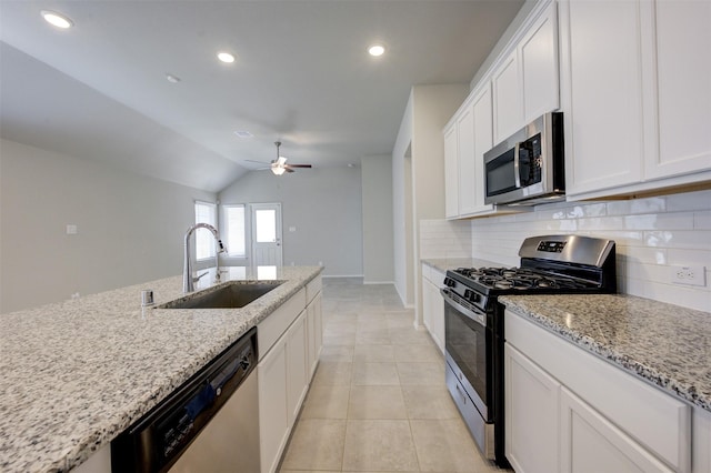 kitchen featuring light tile patterned floors, tasteful backsplash, white cabinets, appliances with stainless steel finishes, and a sink