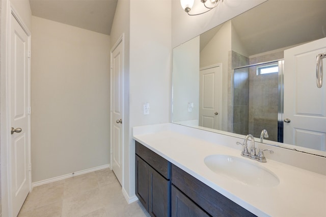 full bath featuring tiled shower, vanity, baseboards, and tile patterned floors