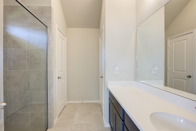 bathroom with tiled shower, tile patterned flooring, vanity, and baseboards