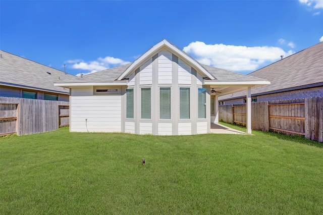 back of property with a fenced backyard, a lawn, and ceiling fan