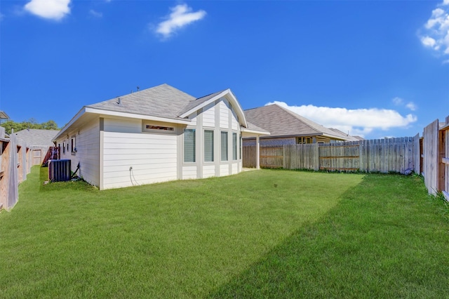 back of house featuring a yard, central AC unit, and a fenced backyard