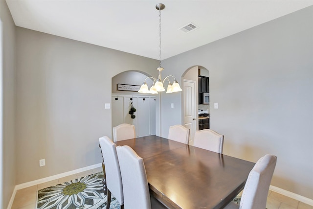 dining area featuring light tile patterned floors, baseboards, visible vents, arched walkways, and a notable chandelier