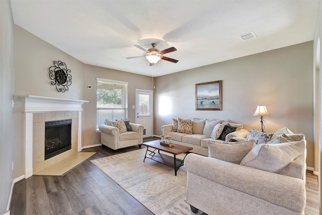 living room with a fireplace, wood finished floors, visible vents, baseboards, and a ceiling fan