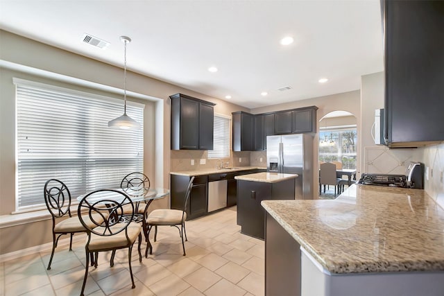 kitchen with arched walkways, stainless steel appliances, a kitchen island, and visible vents