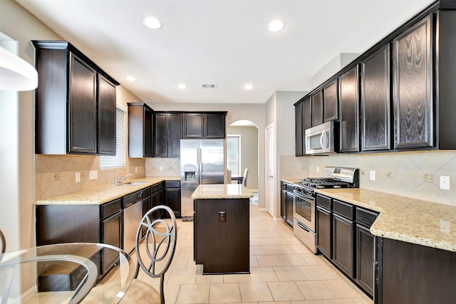 kitchen with visible vents, appliances with stainless steel finishes, light stone counters, and a center island