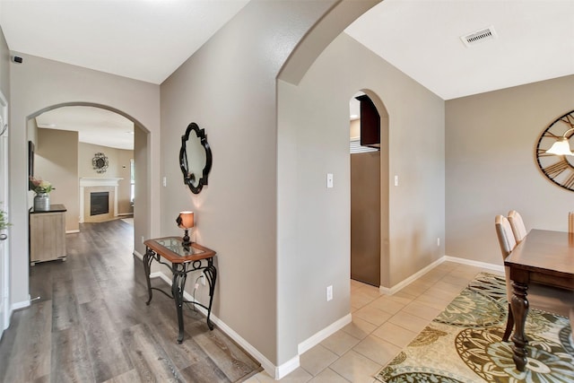 hallway featuring arched walkways, visible vents, and baseboards