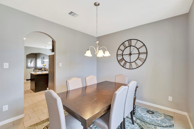 dining space featuring light tile patterned floors, visible vents, arched walkways, and a notable chandelier