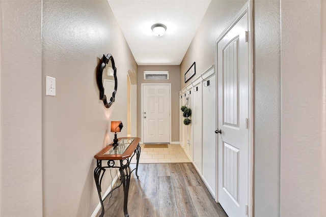 doorway with light wood-type flooring, baseboards, and visible vents