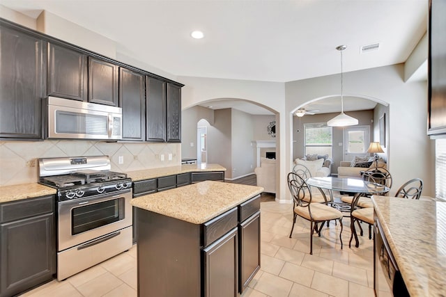 kitchen featuring a center island, a fireplace, stainless steel appliances, visible vents, and backsplash