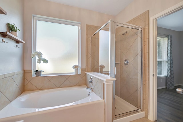 bathroom featuring wood finished floors, a stall shower, and a garden tub