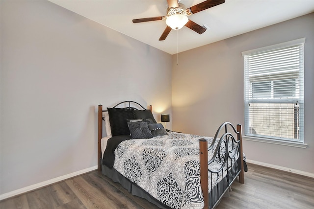 bedroom with ceiling fan, wood finished floors, and baseboards