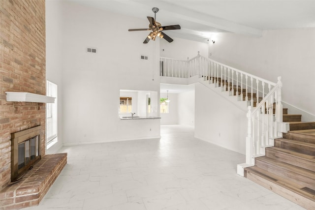 unfurnished living room featuring a fireplace, visible vents, a ceiling fan, marble finish floor, and stairway