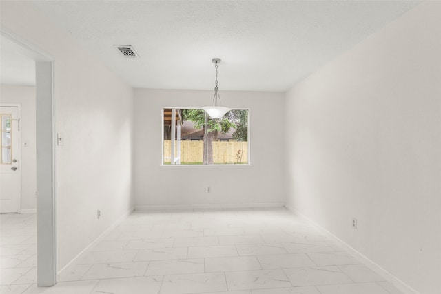 spare room with marble finish floor, visible vents, a textured ceiling, and baseboards