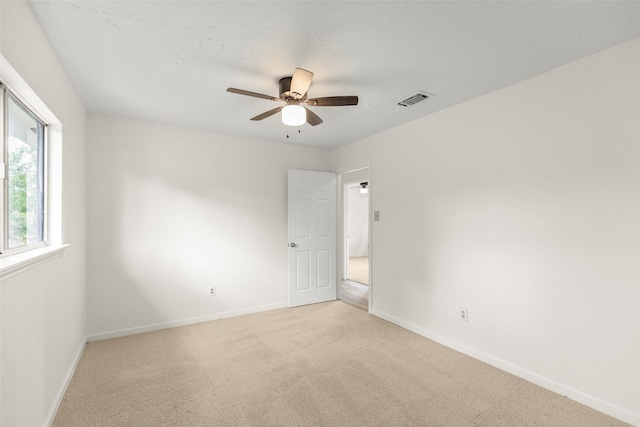 unfurnished room featuring light carpet, a textured ceiling, visible vents, and baseboards