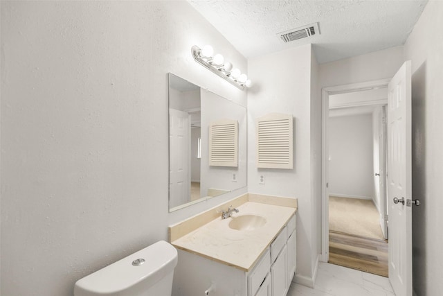 bathroom featuring marble finish floor, visible vents, toilet, a textured ceiling, and vanity