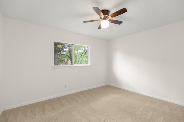 empty room featuring baseboards, a ceiling fan, and light colored carpet