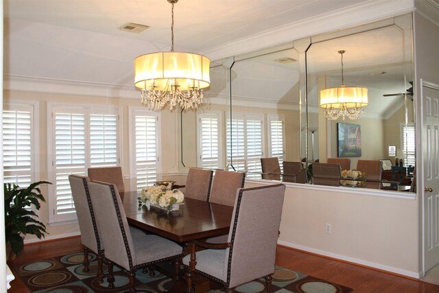 dining space featuring visible vents, wood finished floors, an inviting chandelier, and ornamental molding