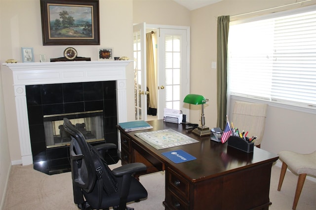 office area featuring a tiled fireplace, lofted ceiling, and carpet