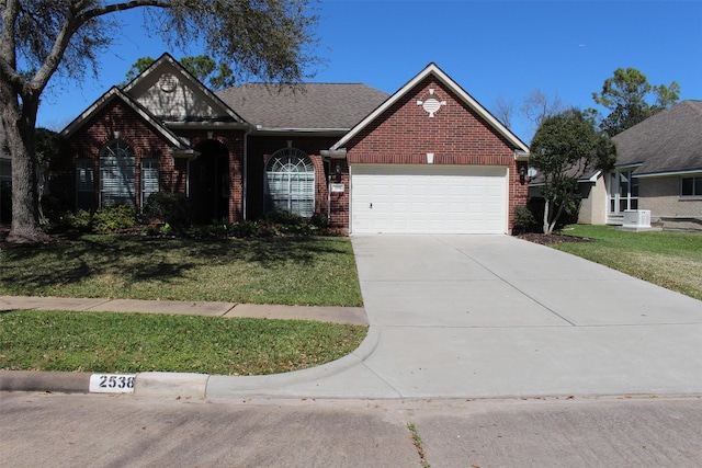 view of front facade with a front yard, an attached garage, brick siding, and driveway