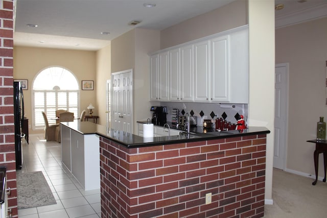 kitchen featuring tasteful backsplash, dark countertops, white cabinetry, a peninsula, and light tile patterned floors