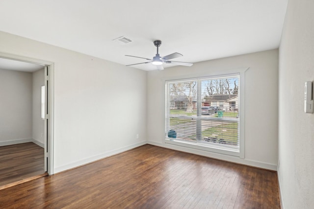 empty room featuring baseboards, dark wood-type flooring, visible vents, and a ceiling fan