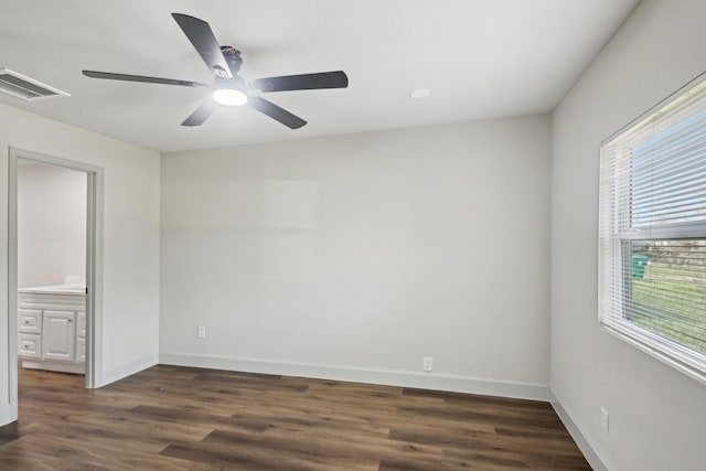 empty room with ceiling fan, dark wood-style flooring, visible vents, and baseboards